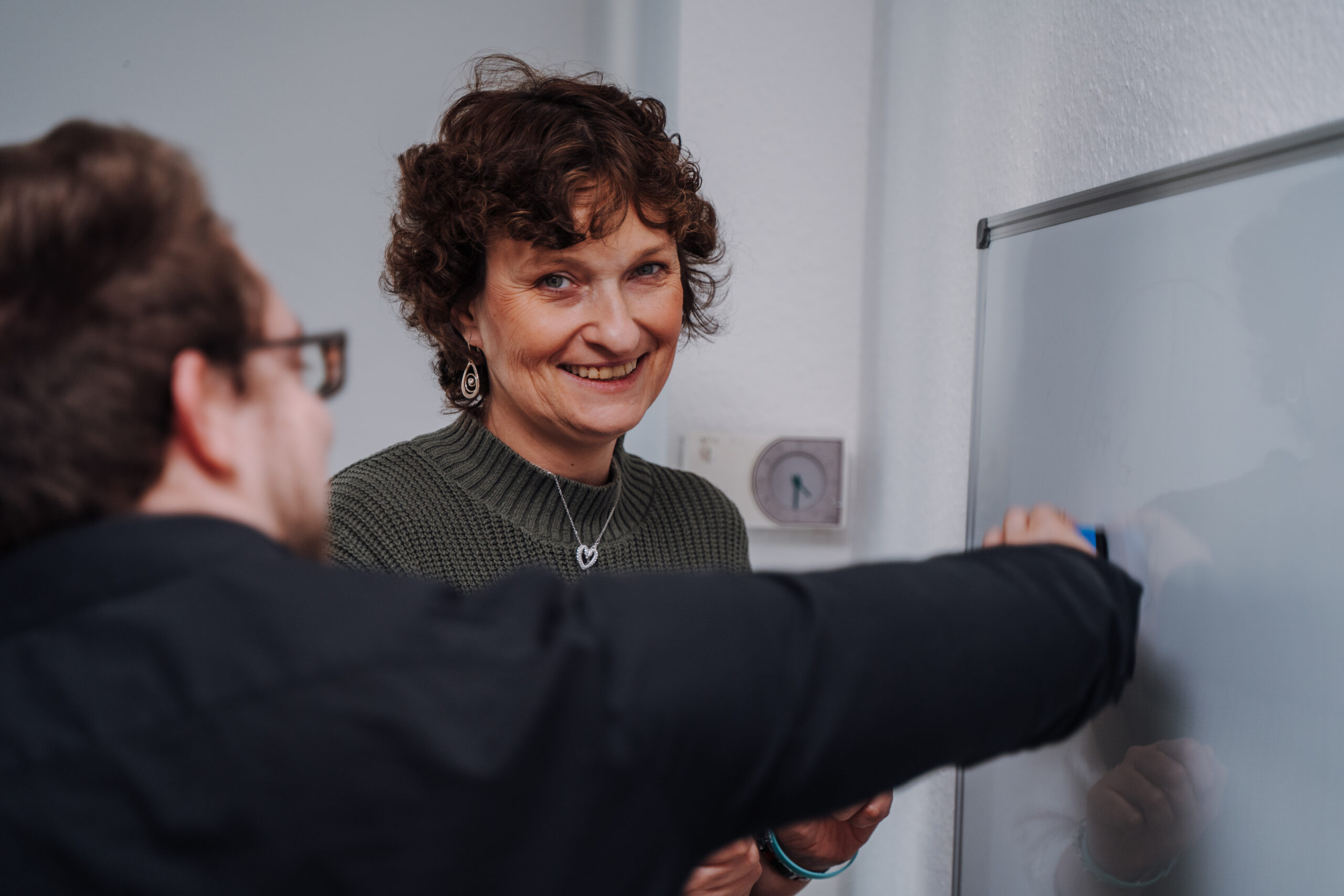 frau steht neben einem mann vor einem whiteboard