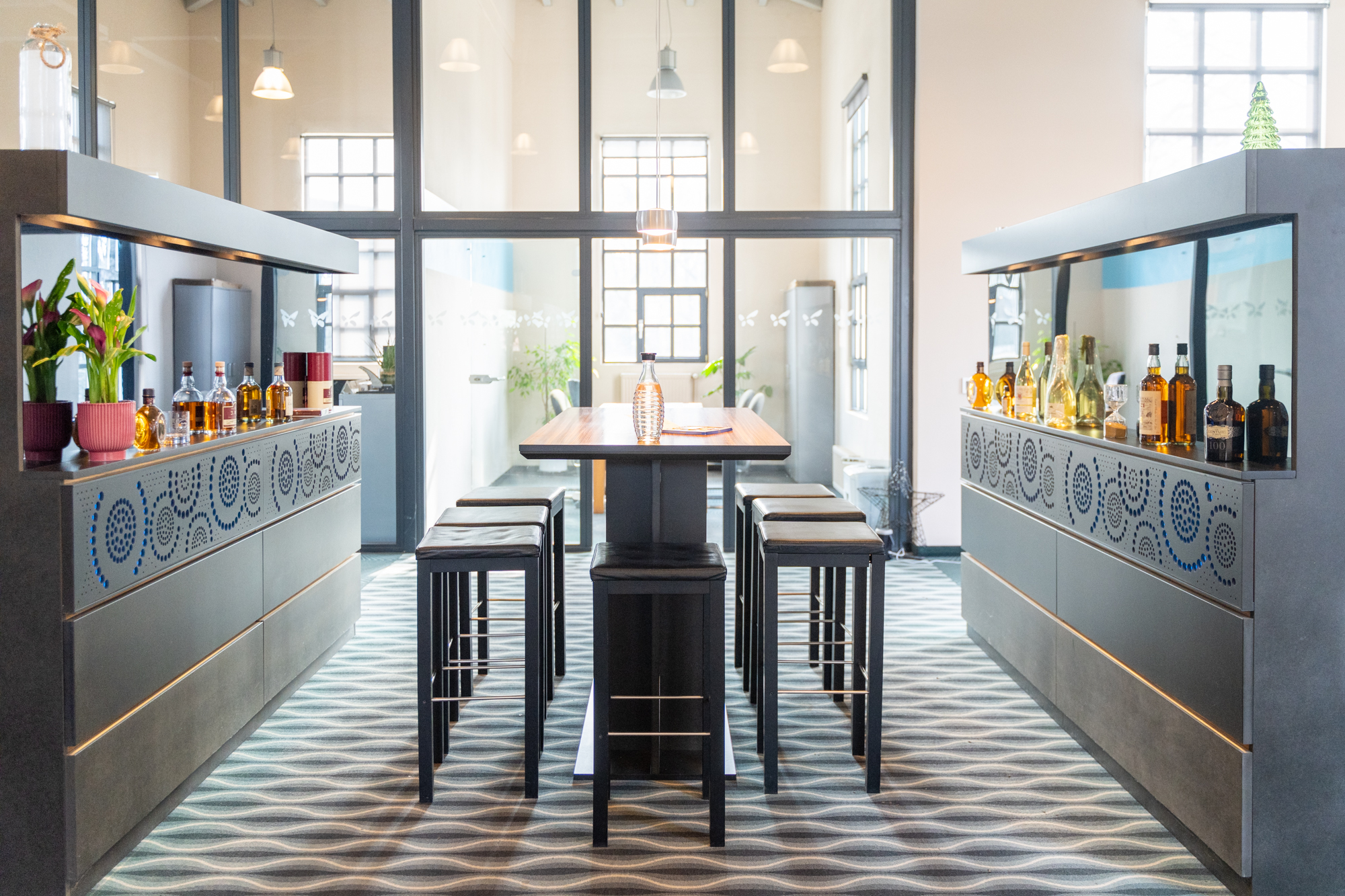 moderne sitzinsel mit hohen hockern und flaschenregalen in bueroraum